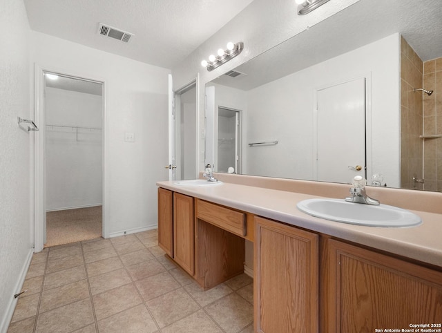 bathroom featuring visible vents, a sink, a spacious closet, and double vanity