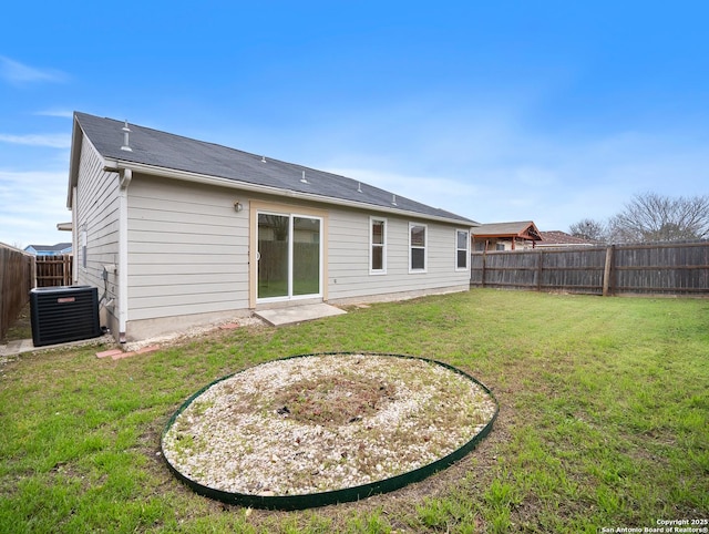 rear view of property with a fenced backyard, central AC unit, and a yard