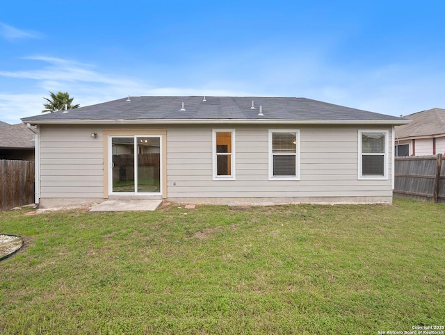 rear view of house with fence and a yard