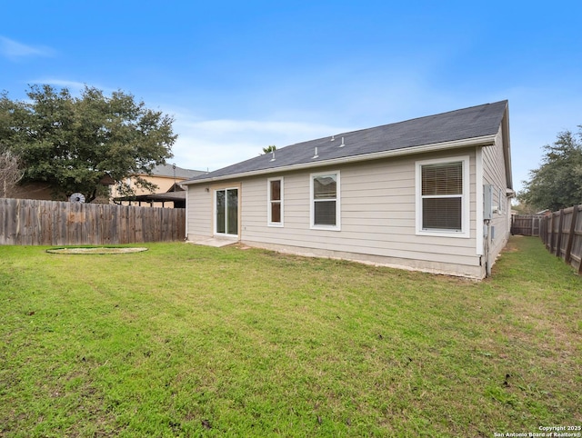 back of property with a fenced backyard and a lawn