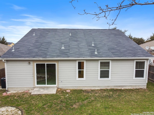 back of house with roof with shingles, fence, and a yard