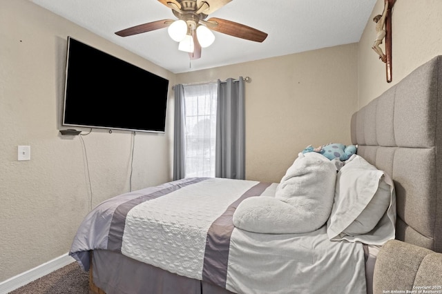 carpeted bedroom featuring baseboards, a ceiling fan, and a textured wall