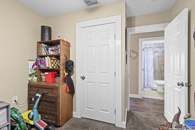 interior space with visible vents, dark carpet, a textured ceiling, and baseboards