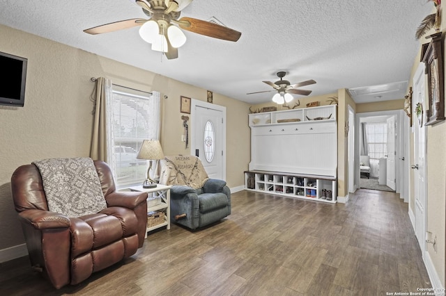 living area featuring a textured ceiling, ceiling fan, wood finished floors, and baseboards