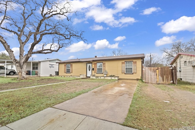 view of front facade featuring driveway, fence, and a front yard