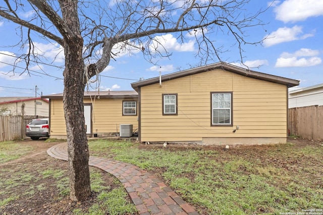 view of property exterior with a yard, fence, and central air condition unit