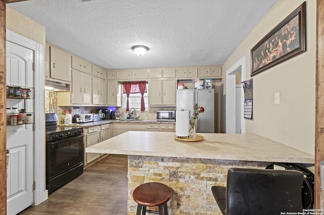 kitchen featuring appliances with stainless steel finishes, a breakfast bar area, light countertops, and cream cabinetry