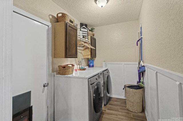 washroom with dark wood finished floors, cabinet space, a textured wall, a textured ceiling, and washer and dryer