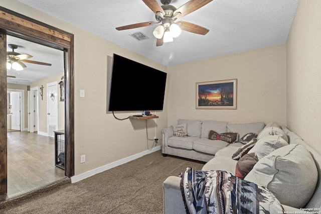 living area featuring baseboards, visible vents, ceiling fan, a textured ceiling, and carpet flooring