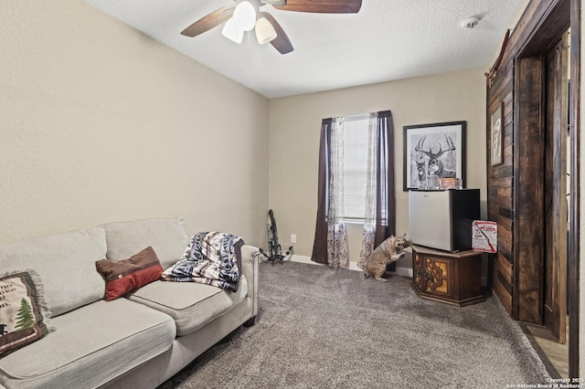 living area with carpet floors, ceiling fan, baseboards, and a textured ceiling