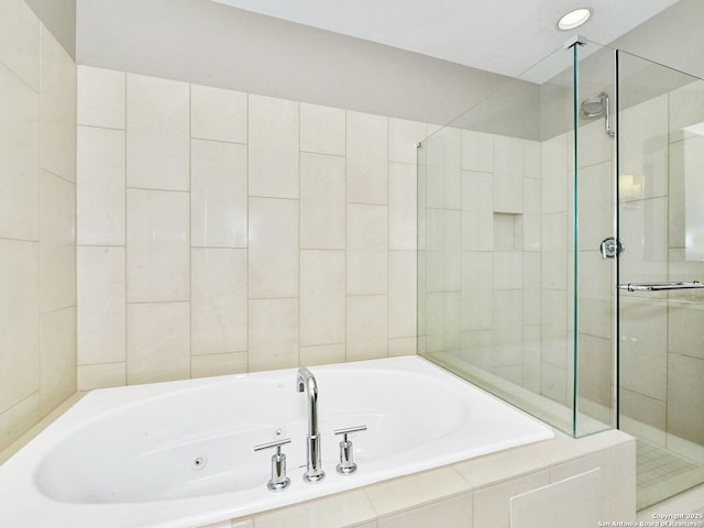 bathroom with a shower stall and a tub with jets