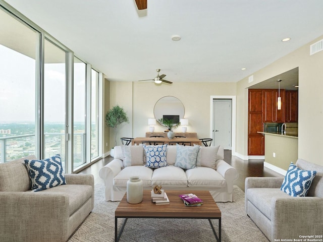 living room featuring light wood-style floors, baseboards, floor to ceiling windows, and ceiling fan