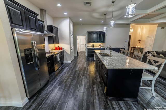 kitchen with a breakfast bar area, stainless steel appliances, visible vents, a sink, and an island with sink