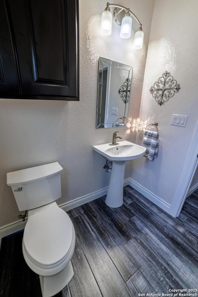 bathroom with wood finished floors, toilet, and baseboards