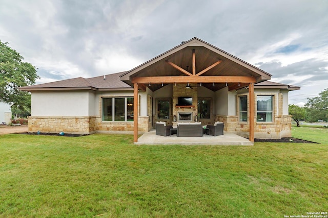 back of property featuring a large fireplace, stone siding, stucco siding, and a patio