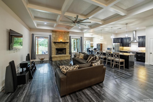 living area with dark wood-style floors, coffered ceiling, beamed ceiling, and a stone fireplace