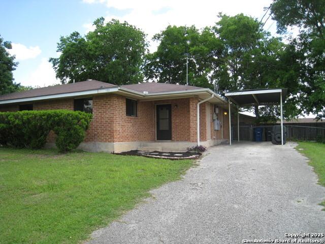 view of front facade with a carport, driveway, and brick siding