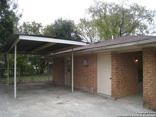 view of car parking featuring an attached carport and fence