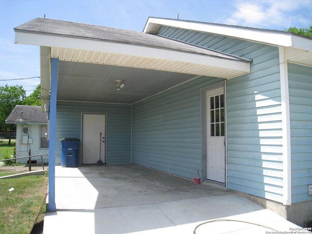 exterior space featuring an attached carport, concrete driveway, and roof with shingles