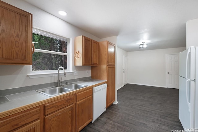 kitchen featuring light countertops, white appliances, brown cabinetry, and a sink