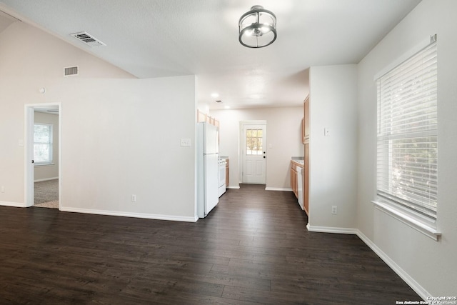 unfurnished room featuring dark wood-style floors, baseboards, visible vents, and vaulted ceiling