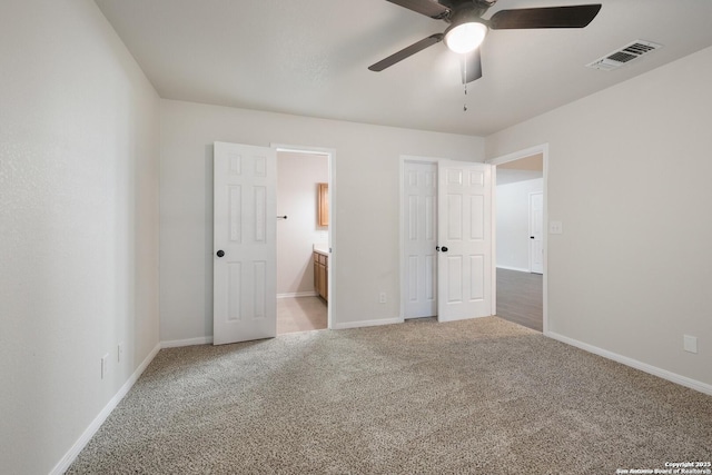 unfurnished bedroom with ceiling fan, light carpet, visible vents, baseboards, and ensuite bath