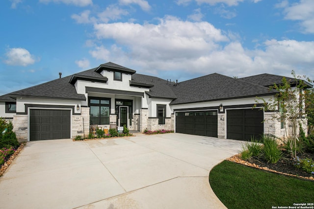 prairie-style house with stone siding, roof with shingles, driveway, and an attached garage