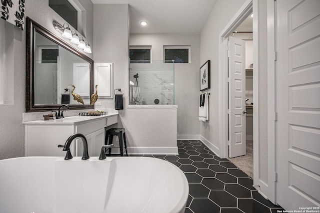 bathroom featuring a freestanding bath, vanity, baseboards, and a walk in shower