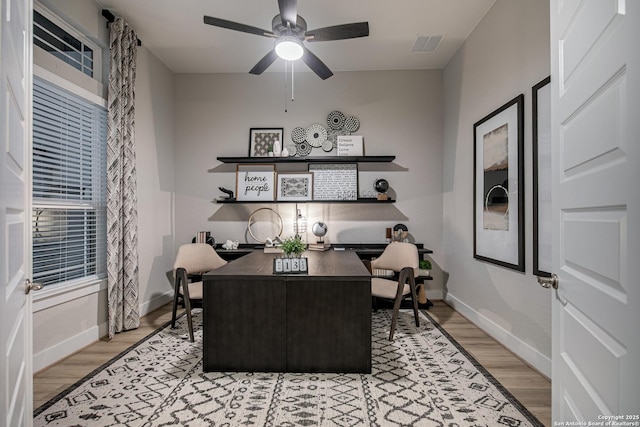 office space featuring baseboards, ceiling fan, visible vents, and light wood-style floors