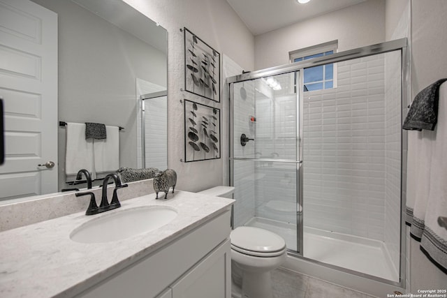 full bathroom with a textured wall, toilet, vanity, tile patterned floors, and a stall shower