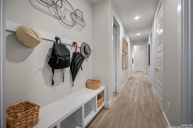 mudroom with light wood-type flooring, a textured wall, baseboards, and recessed lighting