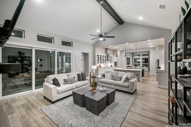 living room featuring visible vents, light wood-style flooring, ceiling fan, beamed ceiling, and high vaulted ceiling