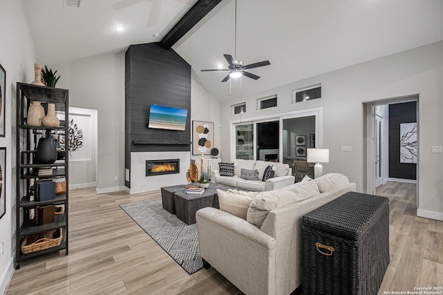 living room featuring light wood-type flooring, a fireplace, high vaulted ceiling, and beam ceiling