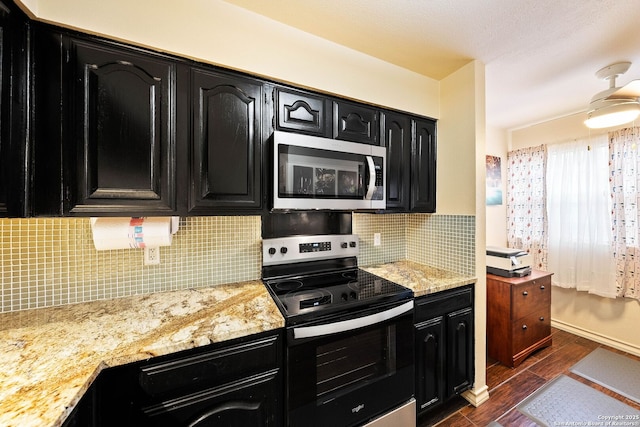 kitchen featuring backsplash, appliances with stainless steel finishes, dark wood-type flooring, light stone countertops, and dark cabinets