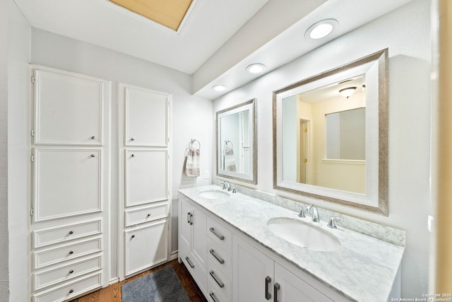 bathroom with double vanity, a sink, and wood finished floors