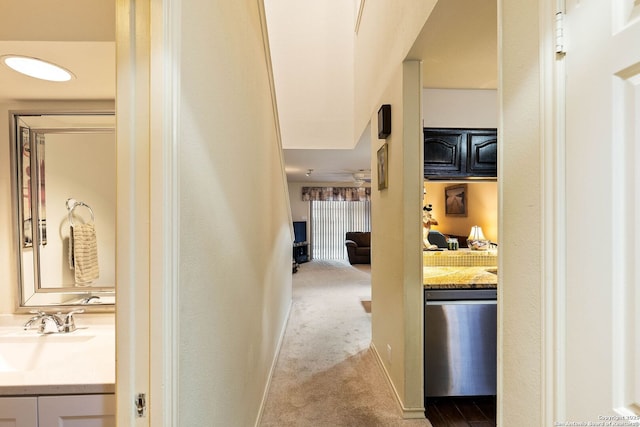 corridor featuring light carpet, baseboards, and a sink