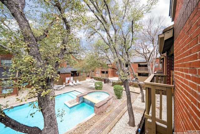 community pool with a patio area and a hot tub