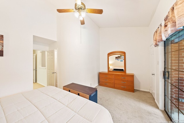 bedroom with light carpet, ceiling fan, and a towering ceiling