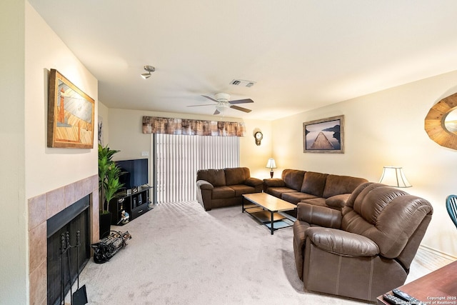 living room with ceiling fan, visible vents, a tiled fireplace, and carpet flooring