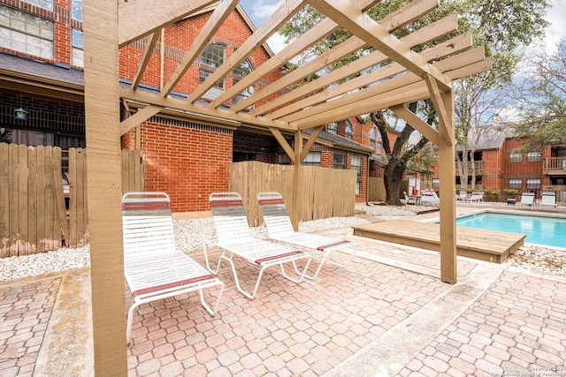 view of patio / terrace with a community pool, fence, and a pergola