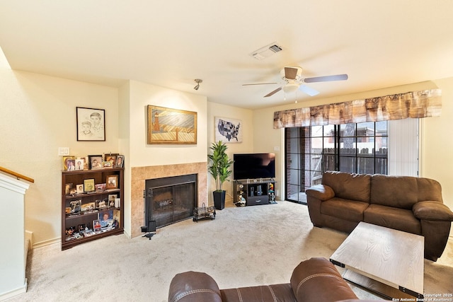 living room featuring light colored carpet, a tile fireplace, visible vents, and ceiling fan