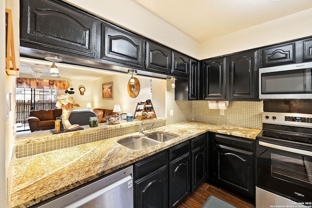 kitchen with dark wood-style floors, stainless steel appliances, backsplash, a sink, and dark cabinetry