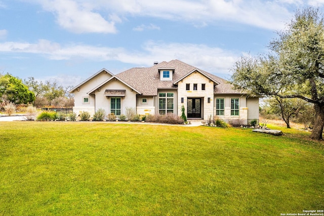 view of front of property featuring stone siding, roof with shingles, and a front yard