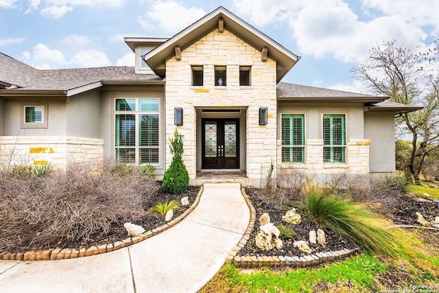 doorway to property featuring stone siding, roof with shingles, stucco siding, and french doors