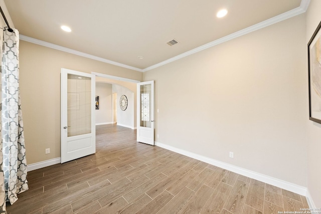 empty room with arched walkways, french doors, visible vents, and wood finish floors