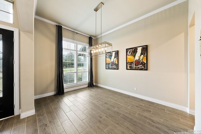 unfurnished dining area with ornamental molding, baseboards, and wood finished floors