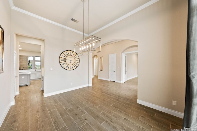 unfurnished dining area with baseboards, visible vents, arched walkways, and wood finished floors