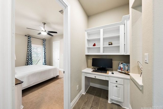 bedroom featuring dark wood-type flooring, built in study area, visible vents, and baseboards