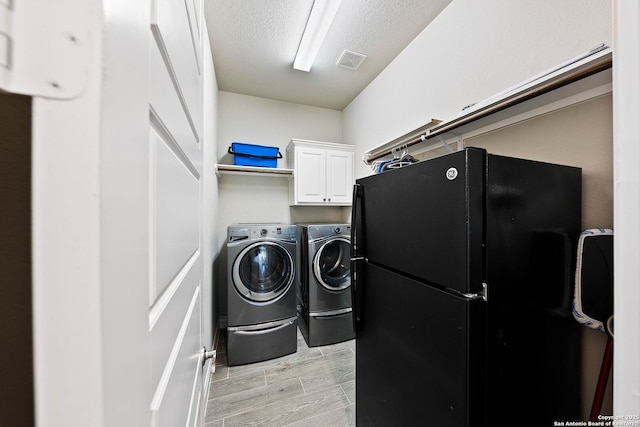 washroom featuring cabinet space, visible vents, independent washer and dryer, wood tiled floor, and a textured ceiling