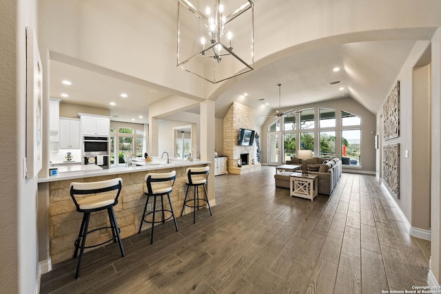 kitchen featuring a stone fireplace, a breakfast bar, white cabinetry, open floor plan, and light countertops